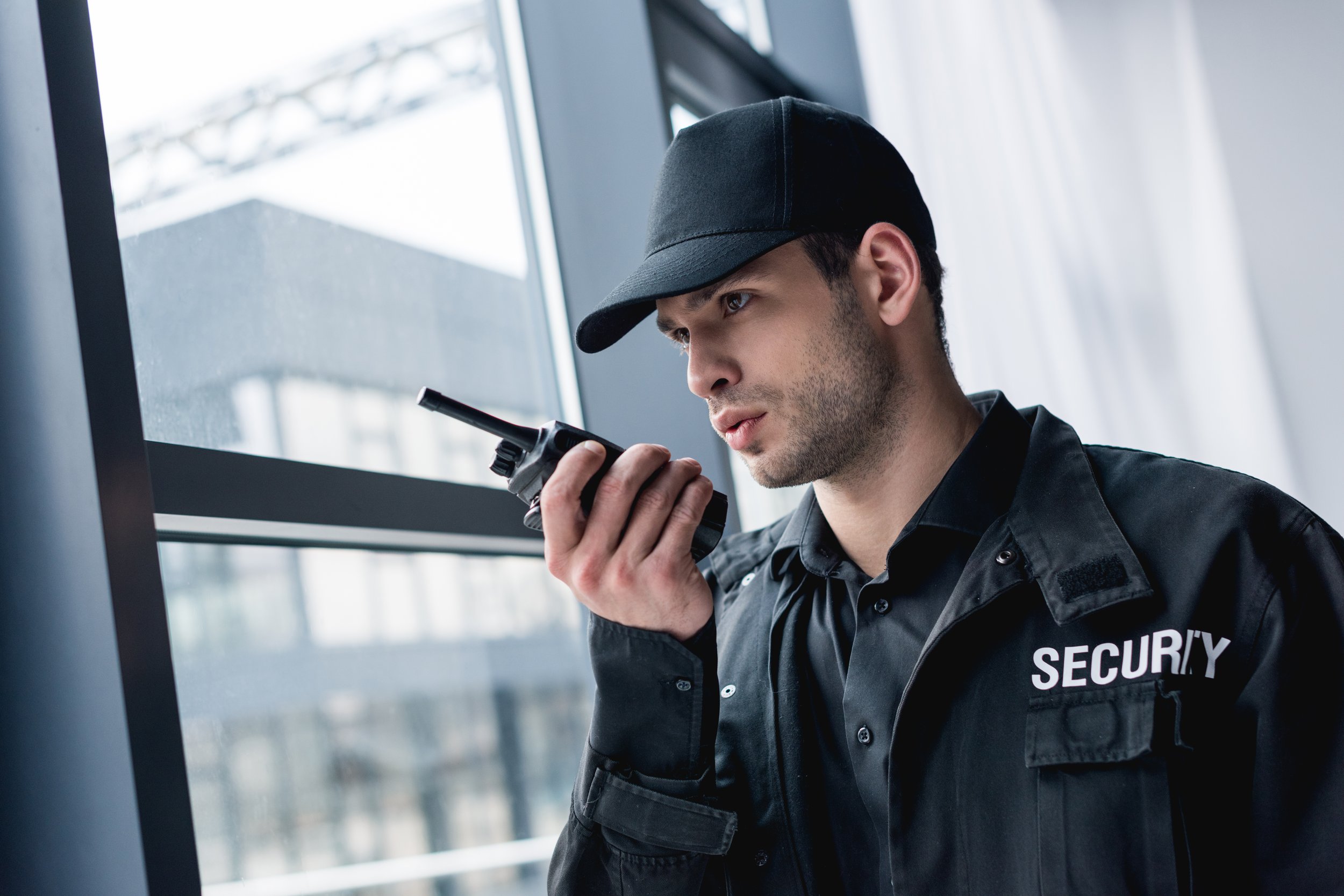 cropped view of guard in uniform talking on walkie-talkie and looking away